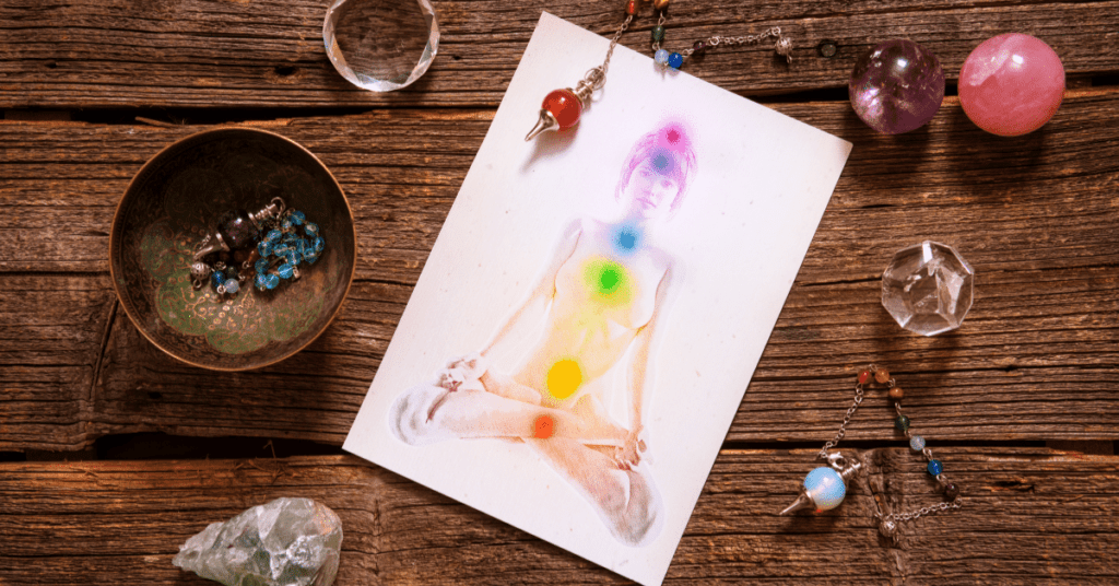 tabletop with crystals and an image of a human body with colourful energy centres