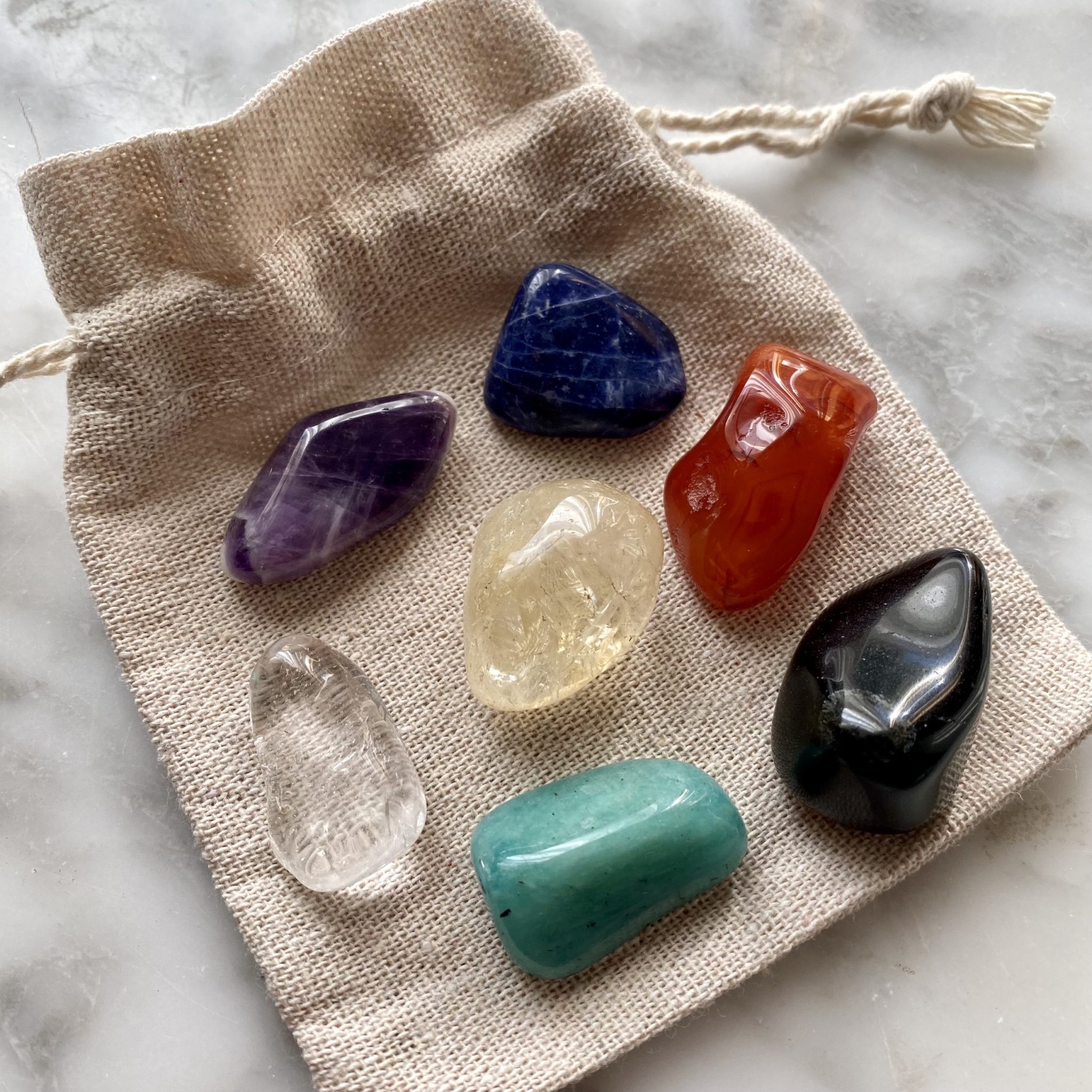 A Chakra Crystal Kit with seven chakra stones and a clear quartz tumbled stone